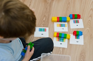 chlopiec korzysta z klockow lego na uczac sie matematyki