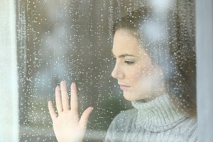smutna kobieta wyglada przez okno