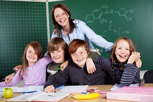 usmiechnieta nauczycielka obejmuje grupe uczniow w klasie