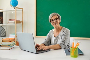 nauczycielka przy biurku przy tablicy w klasie