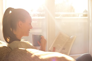 szczesliwa kobieta czyta ksiazke w slonecznym pokoju