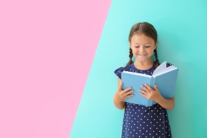 dziewczynka czyta ksiazke na tle pastelowych kolorow