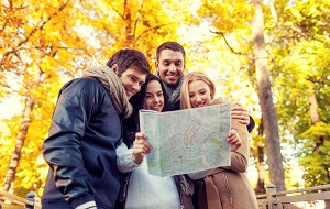 grupa przyjaciol studiuje mape na tle jesiennych drzew
