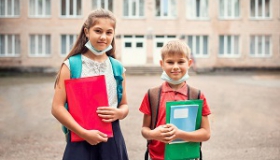 dzieci w maseczkach przed szkola