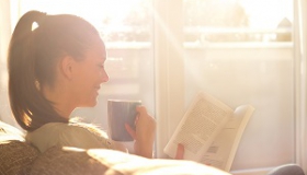 szczesliwa kobieta czyta ksiazke w slonecznym pokoju