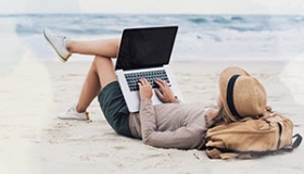 mezczyzna lezacy na plazy z laptopem